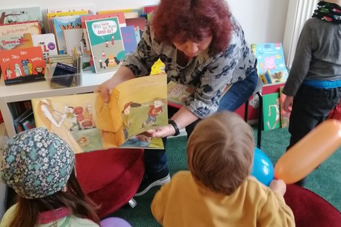 Vorlesepatin Karin liest Kindern aus einem Bilderbuch vor.